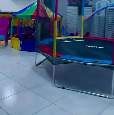 Área coberta com cama elástica, casinha colorida e cadeiras infantis
